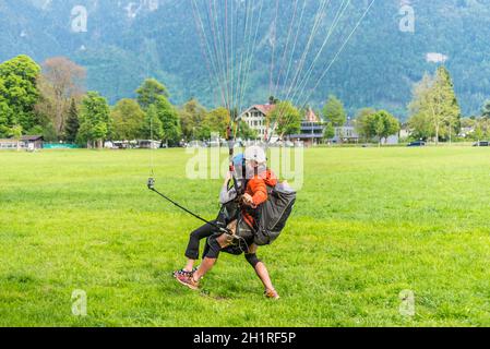 Interlaken, Switzerland - May 26, 2016: Tandem paragliding landing after flight over the Swiss Alps in Interlaken, Switzerland. Stock Photo