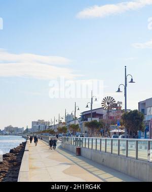 LARNAKA, CHYPRE - 18 FÉVRIER 2019 : les personnes qui marchent à proximité de la ville de Larnaca remblai avec des bâtiments typiques d'architecture en plein soleil. Chypre Banque D'Images