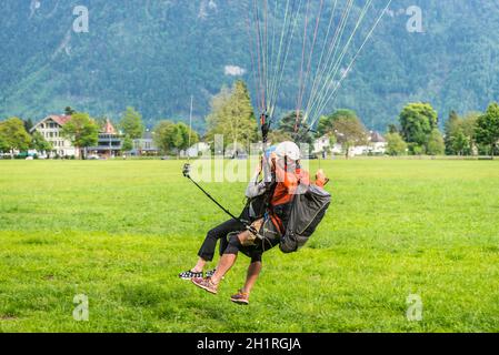 Interlaken, Switzerland - May 26, 2016: Tandem paragliding landing after flight over the Swiss Alps in Interlaken, Switzerland. Stock Photo