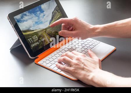 Les mains et les hommes blanc orange ordinateur portable convertible Banque D'Images