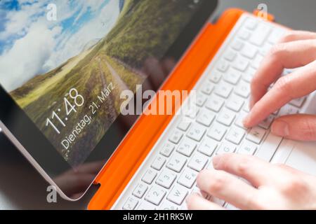 Les mains et les hommes blanc orange ordinateur portable convertible Banque D'Images