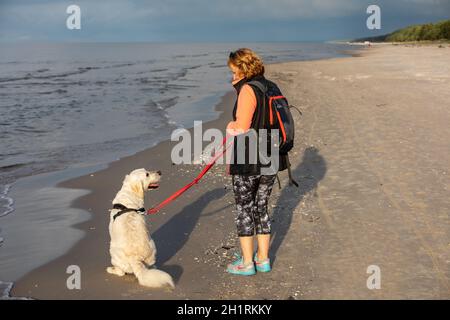 Stegna, Pologne - 4 septembre 2020 : une femme marchant avec son retriever d'or sur la plage de Stegna Banque D'Images