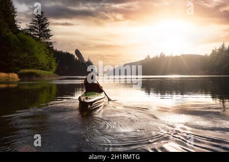 Une fille aventureuse qui fait du kayak dans l'océan Pacifique. Rendu d'art du ciel du coucher du soleil. Prise à San Josef Bay, Cape Scott, dans le nord de l'île de Vancouver, en Colombie-Britannique Banque D'Images