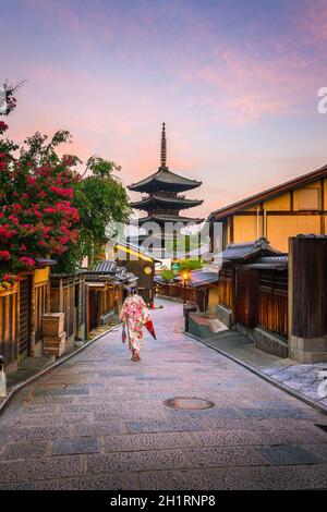 Fille japonaise à Yukata avec parapluie rouge dans la vieille ville de Kyoto, Japon Banque D'Images