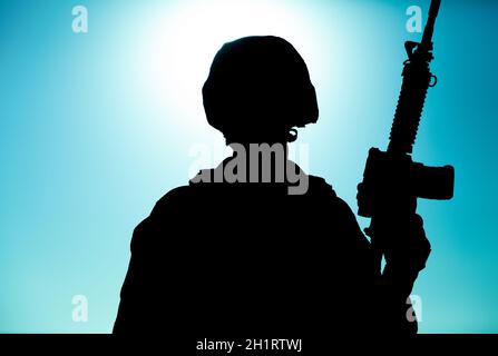 Silhouette de soldat de l'armée, de rifleman d'infanterie des forces spéciales, de chasseur de Marines dans un casque de combat et de munitions debout avec le fusil d'assaut i Banque D'Images