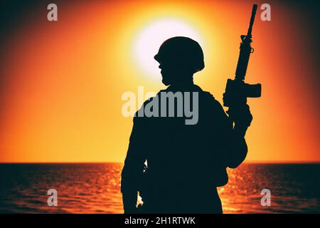 Silhouette de soldat de l'armée, de rifleman d'infanterie des forces spéciales, de chasseur de Marines dans un casque de combat et de munitions debout avec le fusil d'assaut i Banque D'Images