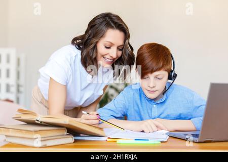 La photo d'une mère aide son fils à faire ses devoirs en ligne. Concept d'apprentissage à distance. Banque D'Images