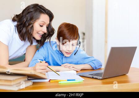 Maman aide son fils à faire ses devoirs en ligne. Concept d'apprentissage à distance. Banque D'Images