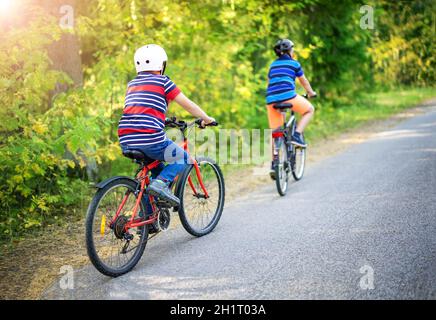 Deux garçons sur des vélos sur route asphaltée en été.Concept d'amitié entre les gens. Banque D'Images