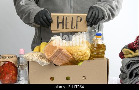 recueille la nourriture, les fruits et les choses dans une boîte en carton pour aider les nécessiteux et les pauvres, le concept de l'aide et du bénévolat Banque D'Images