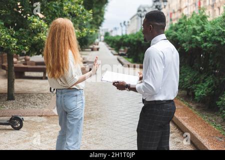 La femme refuse de participer à un sondage ou à un sondage public.La femme fait des gestes avec la main comme rejet. Banque D'Images