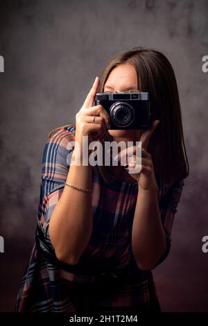 Photographe de fille prend des photos avec un appareil photo rétro, portrait de studio mi-longueur sur un fond gris Banque D'Images