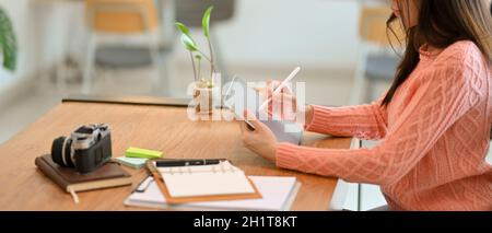 Vue latérale de la belle jeune femme travaillant sur un ordinateur moderne de tablette numérique au café. Freelance, photographe, étudiant d'université. Banque D'Images