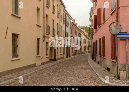 Vue sur les maisons anciennes sur une rue pavée en flexion dans le centre-ville, photographiée dans une lumière claire et nuageux à Mantoue, Lombardie, Italie Banque D'Images