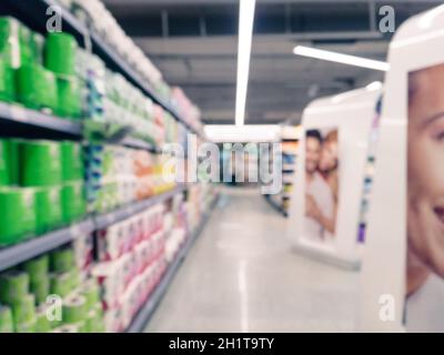Résumé de l'allée de supermarché floue avec des étagères et méconnaissable clients comme arrière-plan Banque D'Images