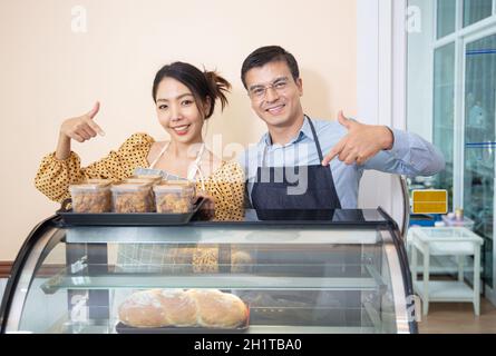 des femmes souriantes tenant des biscuits dans le café en tant que propriétaire de petite entreprise. Banque D'Images