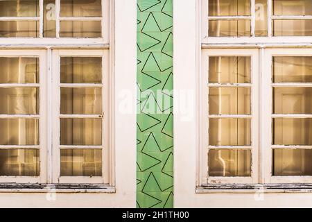 Façade d'une ancienne maison à Aveiro (Portugal) avec des fenêtres en bois blanc décorées de carreaux portugais en vert avec un motif géométrique inhabituel.Gros plan Banque D'Images