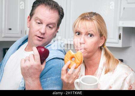 Couple in Kitchen Eating Donut et de café ou de fruits sains. Banque D'Images