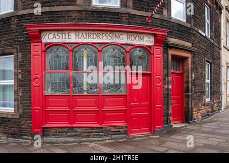 Carlisle, Cumbria, Royaume-Uni, août 2020 - façade courbée d'un magasin de barbiers à façade rouge à l'angle d'une rue dans la ville de Carlisle, Royaume-Uni Banque D'Images