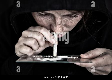 Drogue Addict renifler et ronfler la cocaïne, vitesse, héroïne ou autre drogue avec l'argent roulé sur le miroir avec fond sombre, la dépendance, drogues, déprimé c Banque D'Images