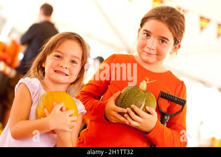 Cute Little Girls Holding leurs citrouilles à une citrouille un jour d'automne. Banque D'Images