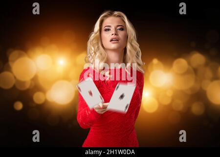 Jeune belle femme émotionnelle jette des cartes sur un fond noir dans le studio.Poker Banque D'Images
