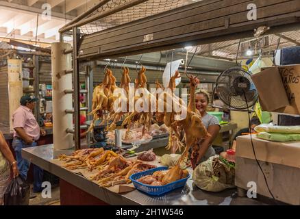 Jeune vendeur de poulet derrière son stand dans la salle du marché de Chetumal, Yucatan, Mexique Banque D'Images