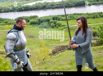 Une dame de chain mail et un chevalier en armure apprendre à tenir une arme et de se défendre contre les coups d'un sabre. Armure chevaleresque et arme. - Un Semi Banque D'Images