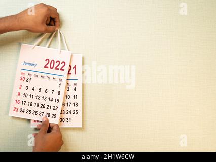 Gros plan de la main remplaçant l'ancien calendrier de 2021 du calendrier de la nouvelle année 2022 sur le mur - concept de fin 2021 ou début de la nouvelle année 2022 Banque D'Images