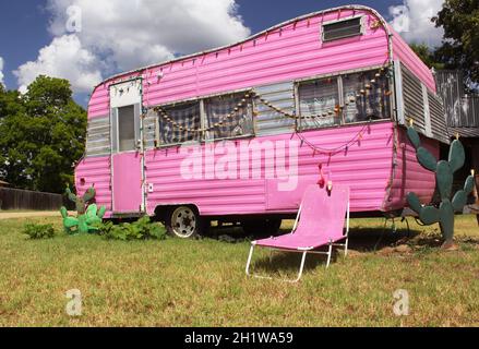 Remorque de voyage rose avec chaise et cactus avec ciel bleu et nuages Banque D'Images