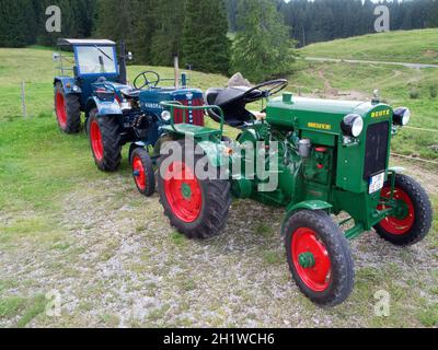 Trois vieux tracteurs se sont alignés l'un derrière l'autre en bleu et vert sur un espace ouvert à côté de l'Alpe Haslacher près du village de vacances de Reichenbach Banque D'Images