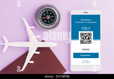 Modèle d'avion, passeport et carte d'immunité sont arrangés application sur smartphone sur fond violet, concept de Voyage pendant la digita pandémique Covid-19 Banque D'Images