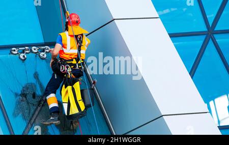 Le nettoyant de fenêtre travaillant sur une façade de verre moderne gratte-ciel Banque D'Images