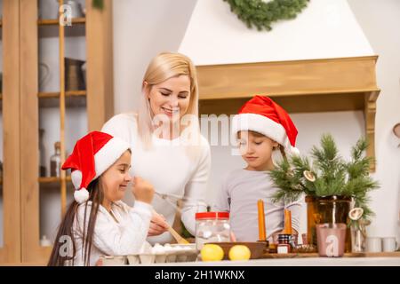 Deux filles vêtues de chapeaux rouges préparent des biscuits, du pain d'épice pour les fêtes du nouvel an, Noël. Coupez les cookies. Banque D'Images