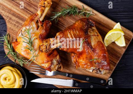 tiges de porc grillées croustillantes sur une planche de bois avec romarin, quartiers de citron et moutarde, vue horizontale depuis le dessus, plat, gros plan Banque D'Images