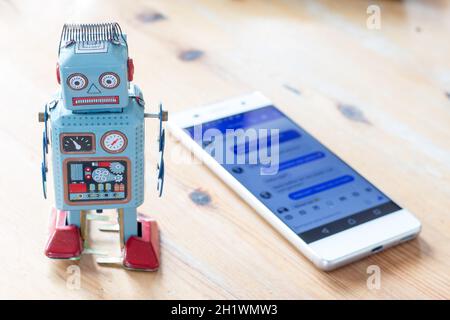 Robot jouet et smartphone, symbole pour chat et messager Banque D'Images