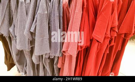 Couleurs de l'arc-en-ciel. Variété de chemises décontractées, t-shirts sur cintres dans un magasin. Gros plan en coton de différentes couleurs vives. Arrière-plan textile. Banque D'Images