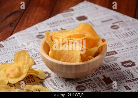 Chips de pommes de terre dans des bols en bois et sur du papier artisanal. En-cas ou bière Banque D'Images