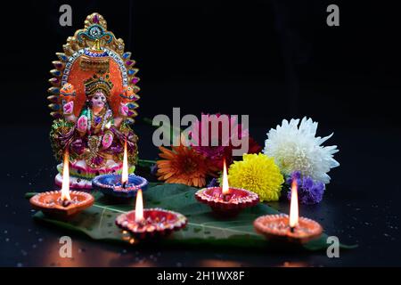 Fait à la main Eco friendly Clay Murti ou Moorti de Hindu Mata Lashmi ou Devi Laxmi Maa.Fleurs décoratives et Diya Dia profond allumé sur la feuille verte.Thème FO Banque D'Images