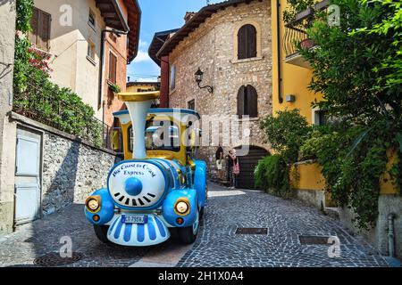 Desenzano del Garda, Italie - 10 juillet 2019 : rue de la ville historique avec le train touristique et les gens, Lombardie. Banque D'Images