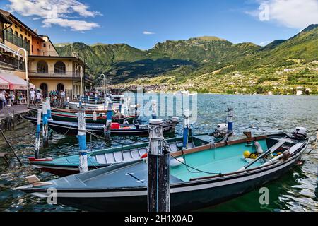 Île de Monte Isola, Lombardie, Italie - 7 juillet 2019 : vue sur le lac d'Iseo, les montagnes et le remblai avec des gens au repos et des bateaux amarrés. Banque D'Images