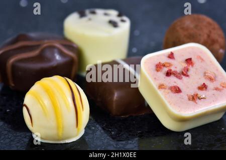 Gros plan sur un assortiment de chocolats de luxe continentaux ou belges sur fond noir Banque D'Images