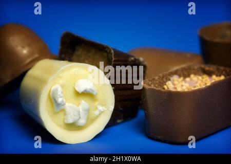 Gros plan sur un assortiment de chocolats de luxe continentaux ou belges sur fond bleu foncé Banque D'Images