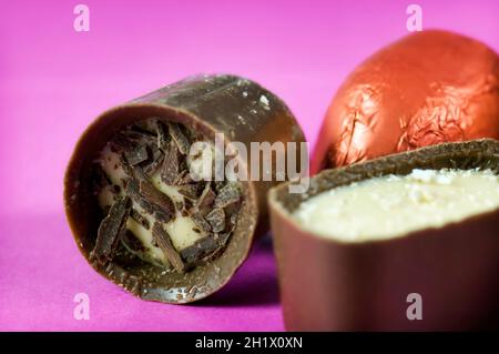 Gros plan de trois chocolats de luxe continentaux ou belges assortis sur fond rose vif Banque D'Images