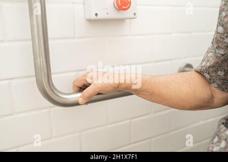 Asiatique senior ou âgée vieille femme patiente utiliser toilettes salle de bains poignée de sécurité dans la salle d'hôpital de soins infirmiers, sain solide concept médical. Banque D'Images