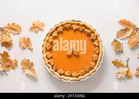 Tarte à la citrouille maison savoureuse avec feuilles de chêne d'automne pour le jour de Thanksgiving sur fond blanc.Vue de dessus.Pose à plat.Bannière automne. Banque D'Images