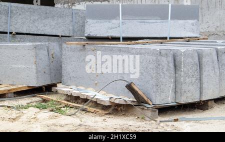 Bordures en granit à facettes sur une palette.Produits en grès de porcelaine lisse sur le chantier.Pierre à bordure, une pile de panneaux de trottoir en béton préparés f Banque D'Images