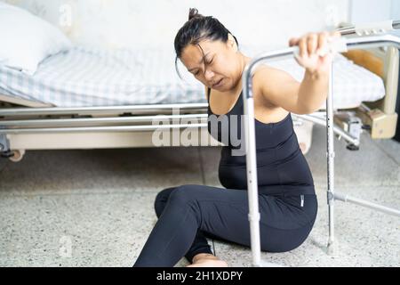 Dame asiatique femme d'âge moyen chute du patient dans la salle de séjour parce que les surfaces glissantes Banque D'Images