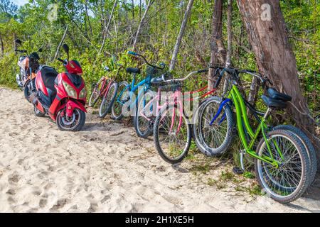 Vélos garés colorés scooters à la plage tropicale mexicaine 88 à Playa del Carmen Mexique. Banque D'Images