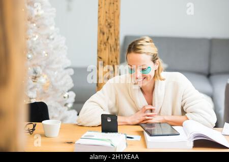 Jeune femme d'affaires portant un peignoir chaleureux et confortable travaillant à distance de la maison en hiver à l'heure de Noël pendant la pandémie de virus corona 2020.Travail à domicile, s Banque D'Images